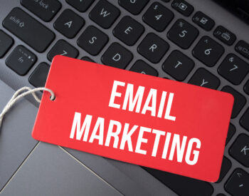 Top view of red paper and the text email marketing on a laptop background.